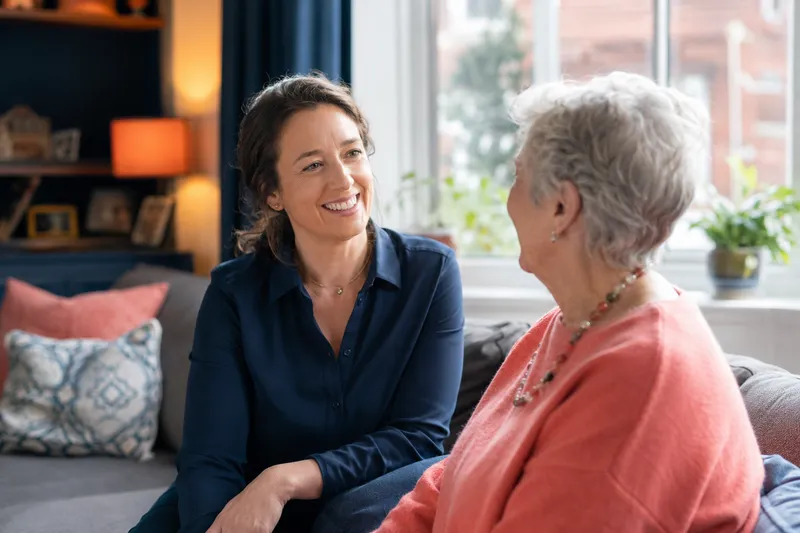 A carer and elderly woman sharing tea in a garden